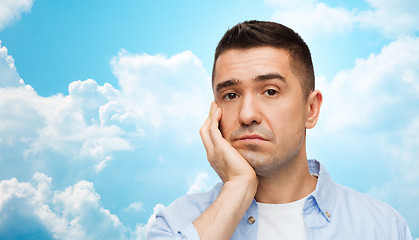 Image showing bored man face over blue sky and clouds background