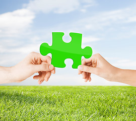 Image showing hands with green puzzle over natural background