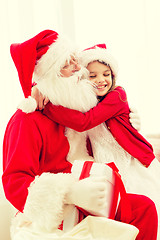 Image showing smiling girl with santa claus and gift at home