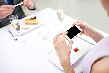 Image showing close up of couple with smartphones at restaurant