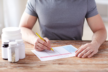 Image showing close up of man with protein jars and diet plan