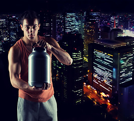 Image showing young male bodybuilder holding jar with protein