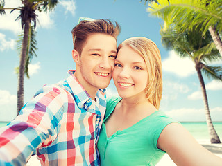 Image showing smiling couple with smartphone on summer beach