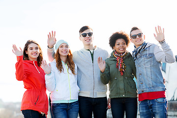 Image showing happy teenage friends waving hands on city street