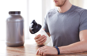 Image showing close up of man with protein shake bottle and jar