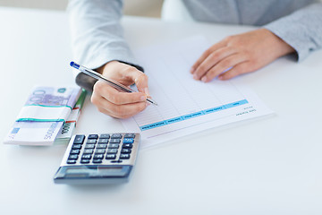 Image showing close up of hands counting money with calculator