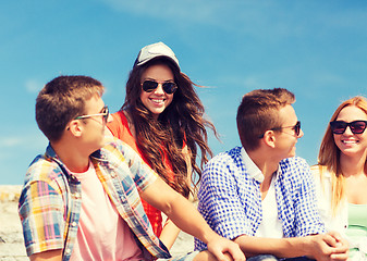 Image showing group of smiling friends sitting on city street