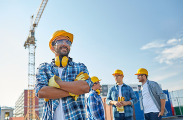 Image showing group of smiling builders in hardhats outdoors