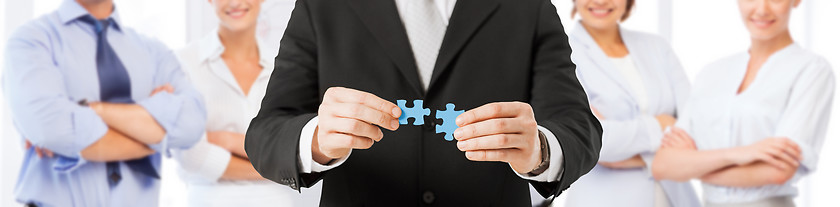 Image showing man matching puzzle pieces over business team