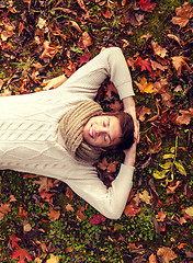 Image showing smiling young man lying on ground in autumn park