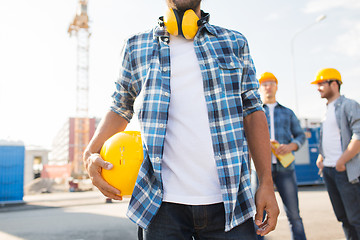 Image showing close up of builder holding hardhat at building