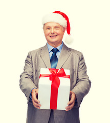 Image showing smiling man in suit and santa helper hat with gift