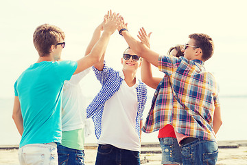 Image showing group of smiling friends making high five outdoors