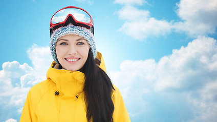 Image showing happy young woman in ski goggles over blue sky