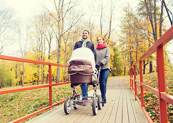 Image showing smiling couple with baby pram in autumn park