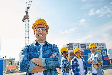 Image showing group of smiling builders in hardhats outdoors