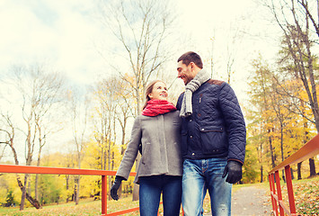 Image showing smiling couple hugging on bridge in autumn park