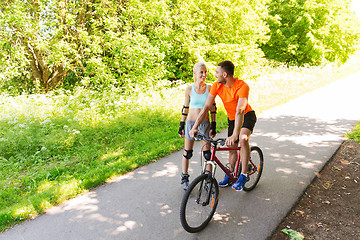 Image showing happy couple with rollerblades and bicycle riding