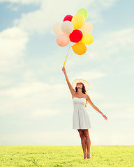 Image showing smiling young woman in sunglasses with balloons