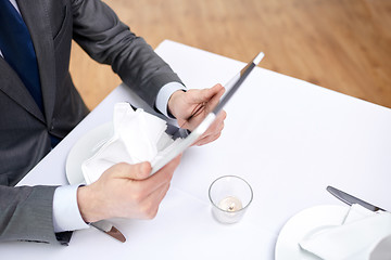 Image showing close up of man with tablet pc at restaurant