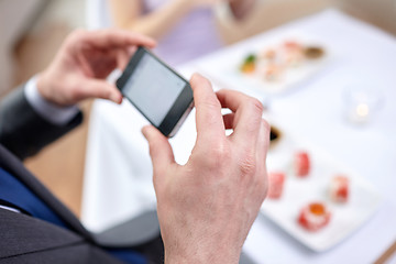 Image showing close up of couple with smartphones at restaurant