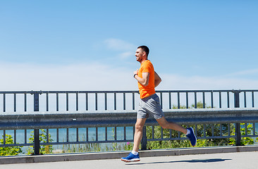 Image showing smiling young man running at summer seaside