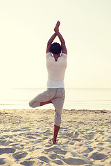 Image showing man making yoga exercises outdoors from back