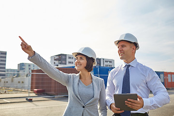 Image showing happy builders in hardhats with tablet pc outdoors