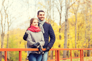 Image showing smiling couple hugging on bridge in autumn park