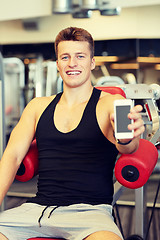 Image showing smiling young man with smartphone in gym