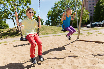 Image showing two happy kids swinging on swing at playground