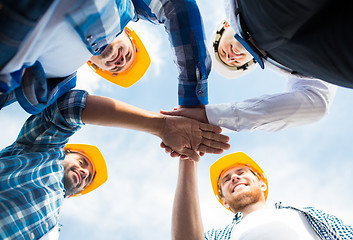 Image showing close up of builders in hardhats with hands on top