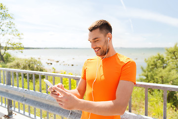 Image showing smiling young man with smartphone and earphones