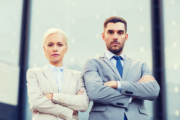 Image showing serious businessmen standing over office building