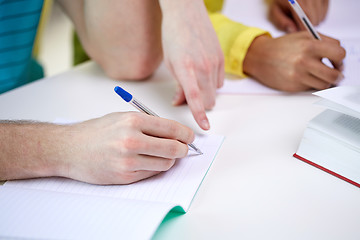 Image showing close up of students hands writing to notebooks