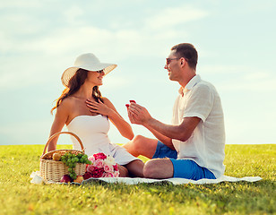 Image showing smiling couple with small red gift box on picnic