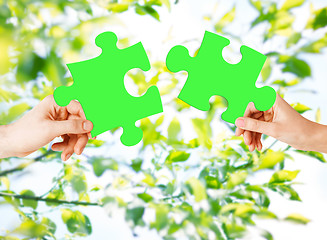 Image showing hands with green puzzle over natural background