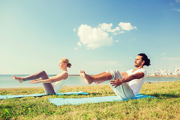 Image showing smiling couple making yoga exercises outdoors