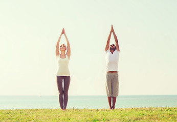 Image showing smiling couple making yoga exercises outdoors