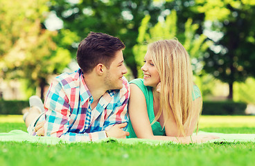 Image showing smiling couple lying on blanket in park