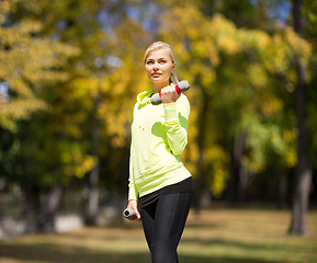 Image showing sporty woman with light dumbbells outdoors