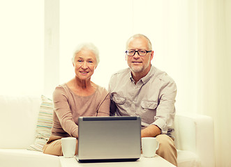 Image showing happy senior couple with laptop and cups at home
