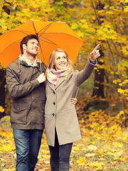 Image showing smiling couple with umbrella in autumn park