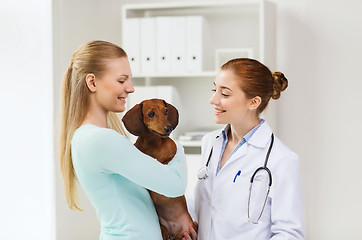 Image showing happy woman with dog and doctor at vet clinic