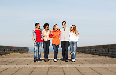 Image showing happy teenage friends walking along city street