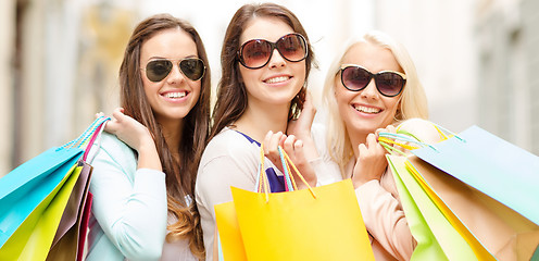 Image showing three smiling girls with shopping bags in city