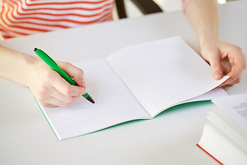 Image showing close up of female hands writing to notebook