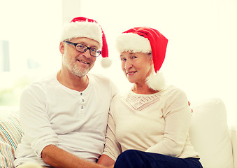 Image showing happy senior couple in santa helper hats at home