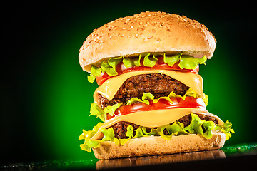 Image showing Tasty and appetizing hamburger on a darkly green