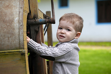 Image showing 2 years old curious Baby boy managing with old agricultural Mach